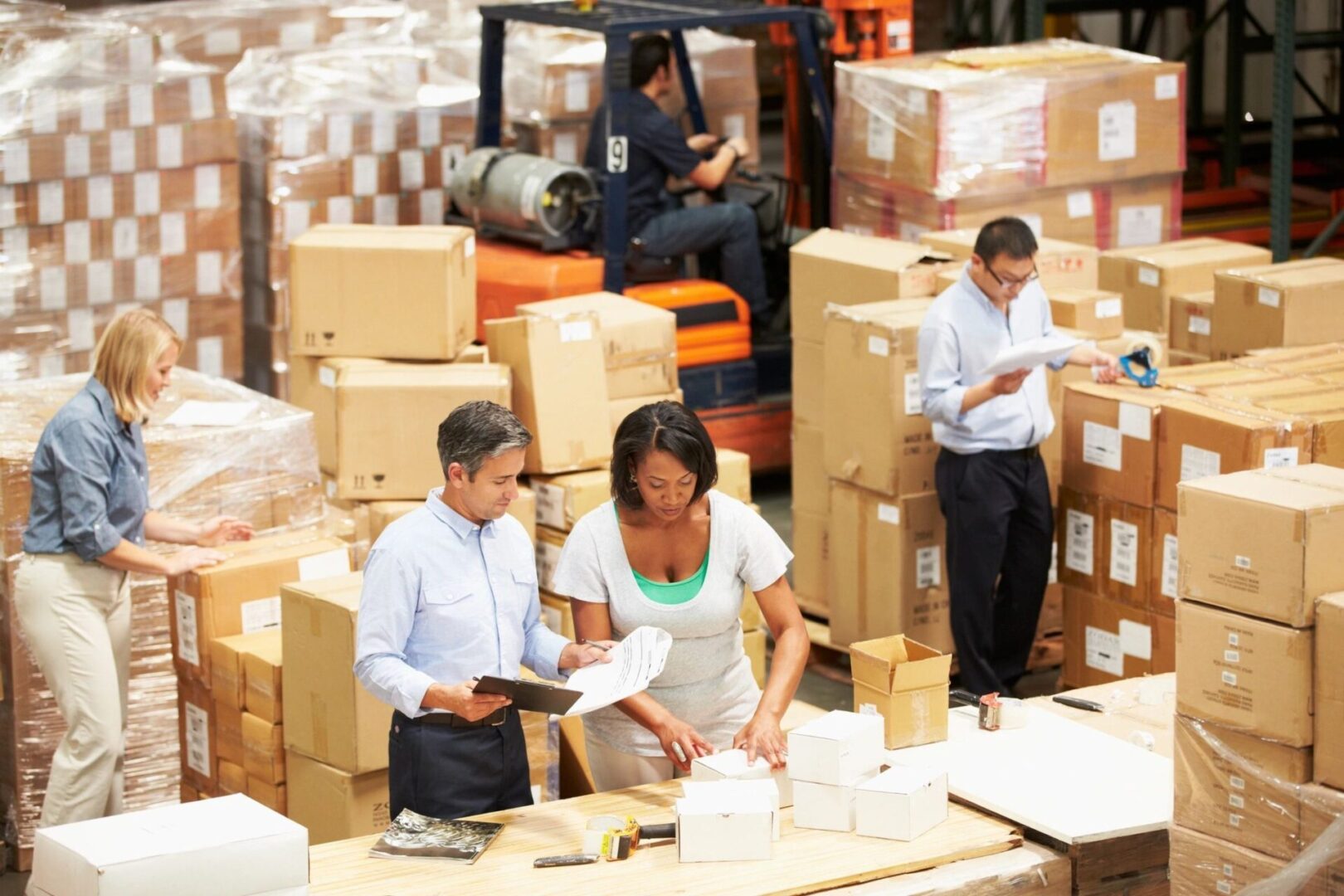 A group of people in warehouse with boxes.