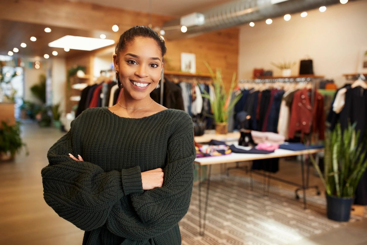 A woman standing in front of a table with clothes on it.