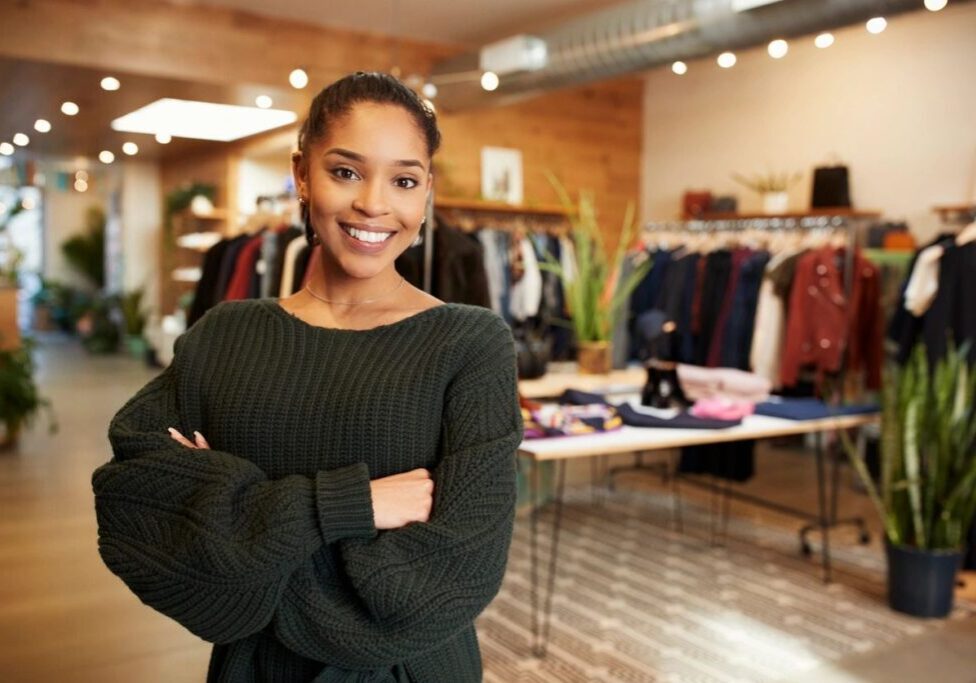 fm_f_YogygGJ A woman standing in front of a table with clothes on it.