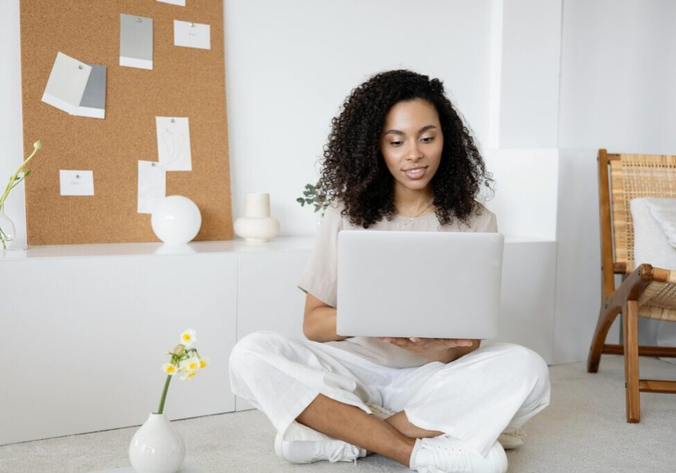 A woman sitting on the floor with her laptop.